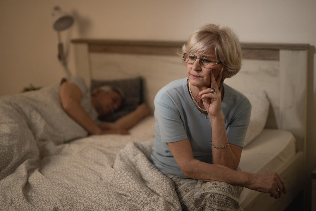 Pensive older woman sitting on bed