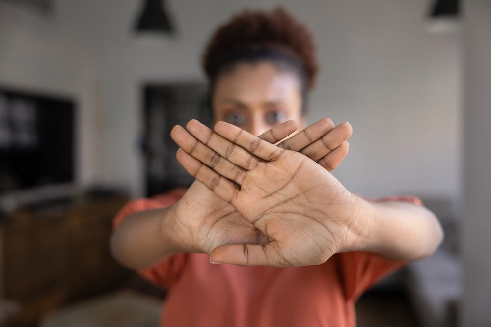 Black woman with hair pulled back gestures stop to viewer 