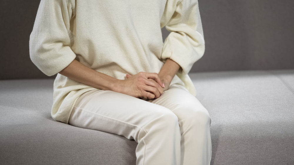 Middle-aged White woman in cream outfit with waiting with hands in lap