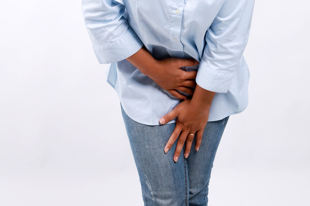 Woman with brown skin holds hands protectively over her pelvis.jpg
