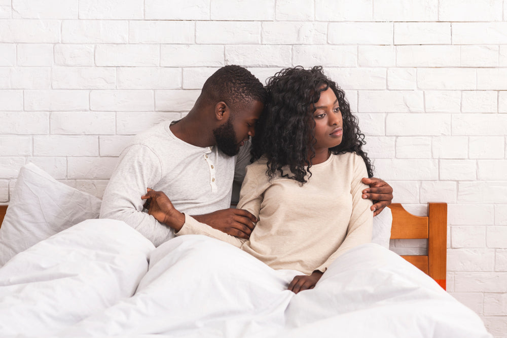 Young Black woman looks sadly away from her worried male partner
